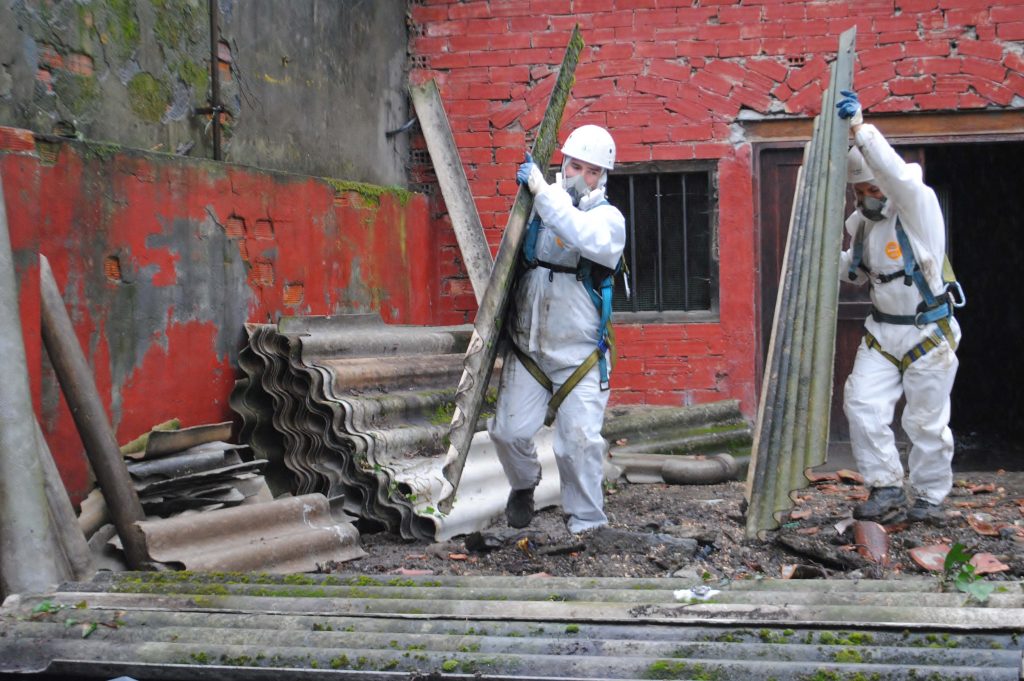 Asbestos in Construction. Workers handling corrugated asbestos roof panels. 